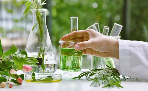 녹색 액체가 담긴 유리잔을 들고 있는 연구원